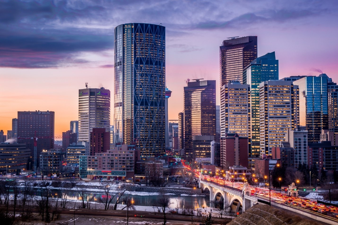 Photo of Downtown Calgary looking south over the Centre Street bridge, with purple and pink skies at sunrise